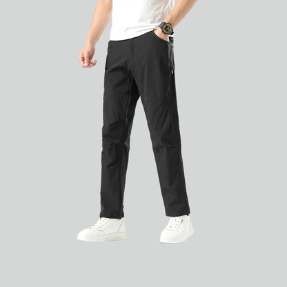 Weatherproof outdoor trousers for men in black, gray, and green colours with adjustable waistband and reinforced panels