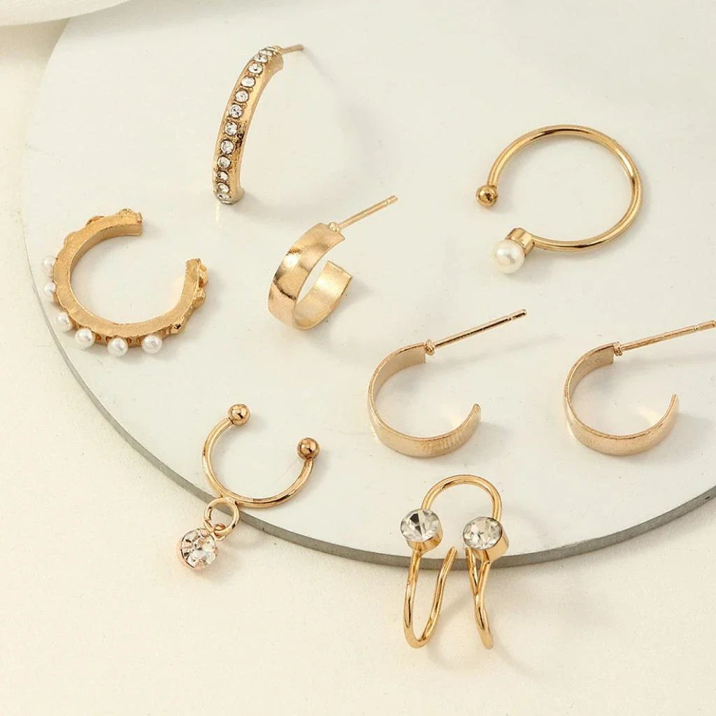 A set of 8 sophisticated gold-toned pearl stud earrings with unique, eye-catching designs