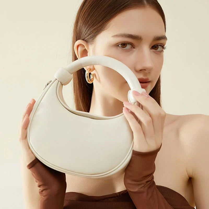 Elegant rose pink leather crescent-shaped crossbody bag with adjustable strap and zipper closure