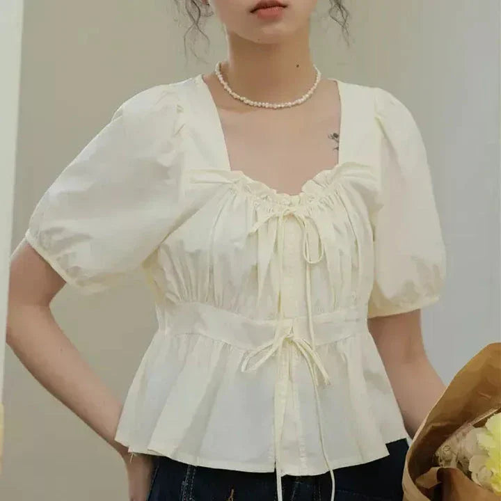 Elegant vintage-inspired blouse with square neckline, puff sleeves, and lace-up details for a timeless, sophisticated look