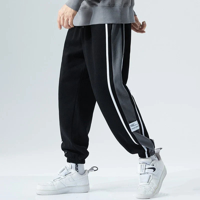 Plus-size men's loose sports trousers with ankle ties, made of premium polyester fabric in classic colours for versatile, comfortable activewear.