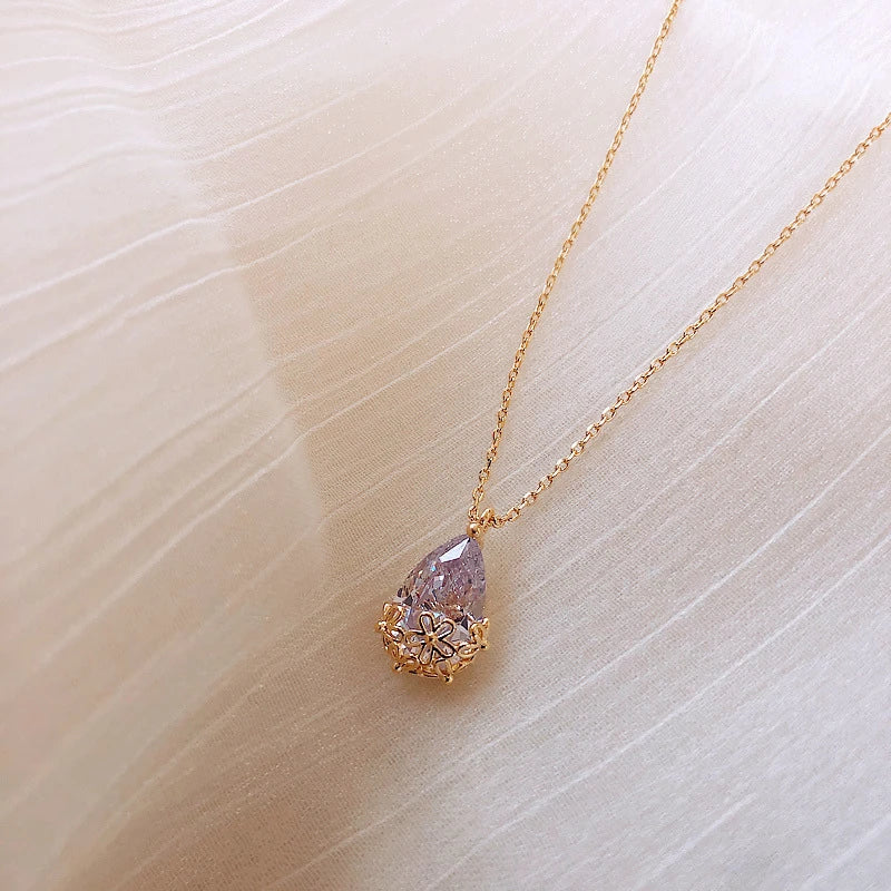Close-up shot of a silver-plated crystal water drop pendant necklace on a plain background