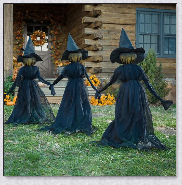 Three tall, black-robed witch figures with faceless glowing heads, standing together and holding hands, creating a spooky outdoor Halloween display