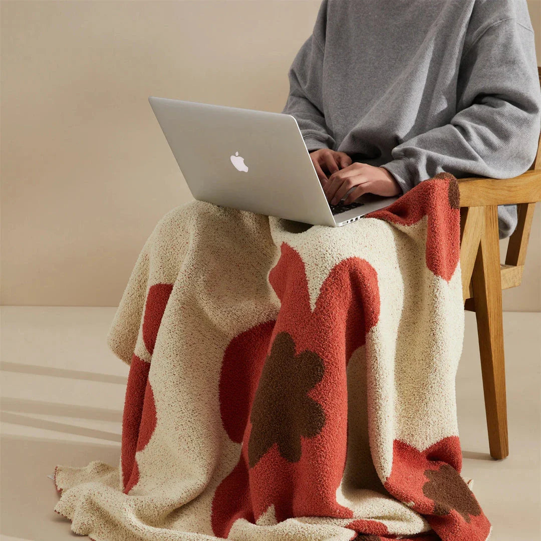 Cosy floral knitted throw blanket in red, grey, and orange colours for year-round comfort and style