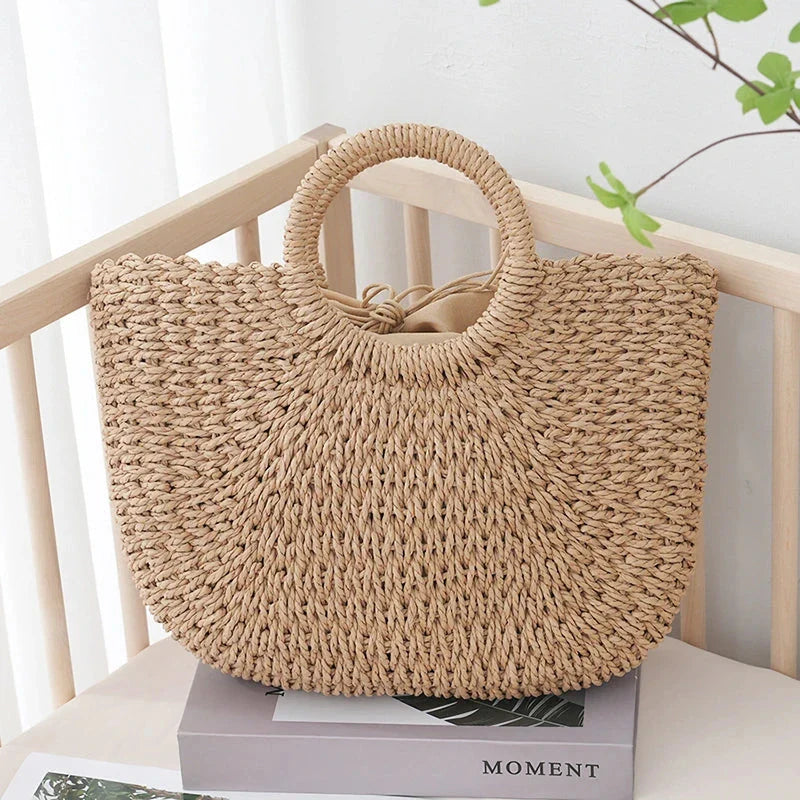 Premium handwoven straw beach tote with a casual half-moon shape and secure string closure, perfect for summer outings