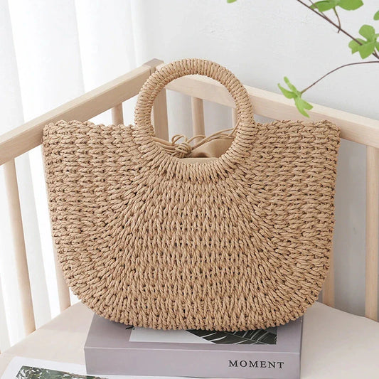 Premium handwoven straw beach tote with a casual half-moon shape and secure string closure, perfect for summer outings