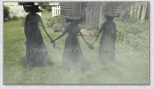 Three tall, black-robed witch figures with faceless glowing heads, standing together and holding hands, creating a spooky outdoor Halloween display