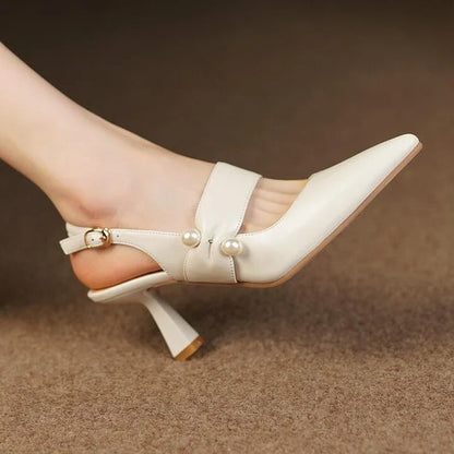 Pair of white high heel sandals with pearl embellishments, showcasing a unique and fashionable design