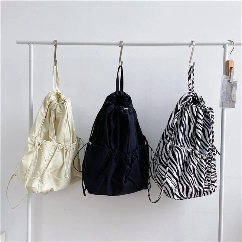 A stylish drawstring bucket bag in white, black, or brown colour options, featuring a spacious interior and adjustable closure for modern British women.