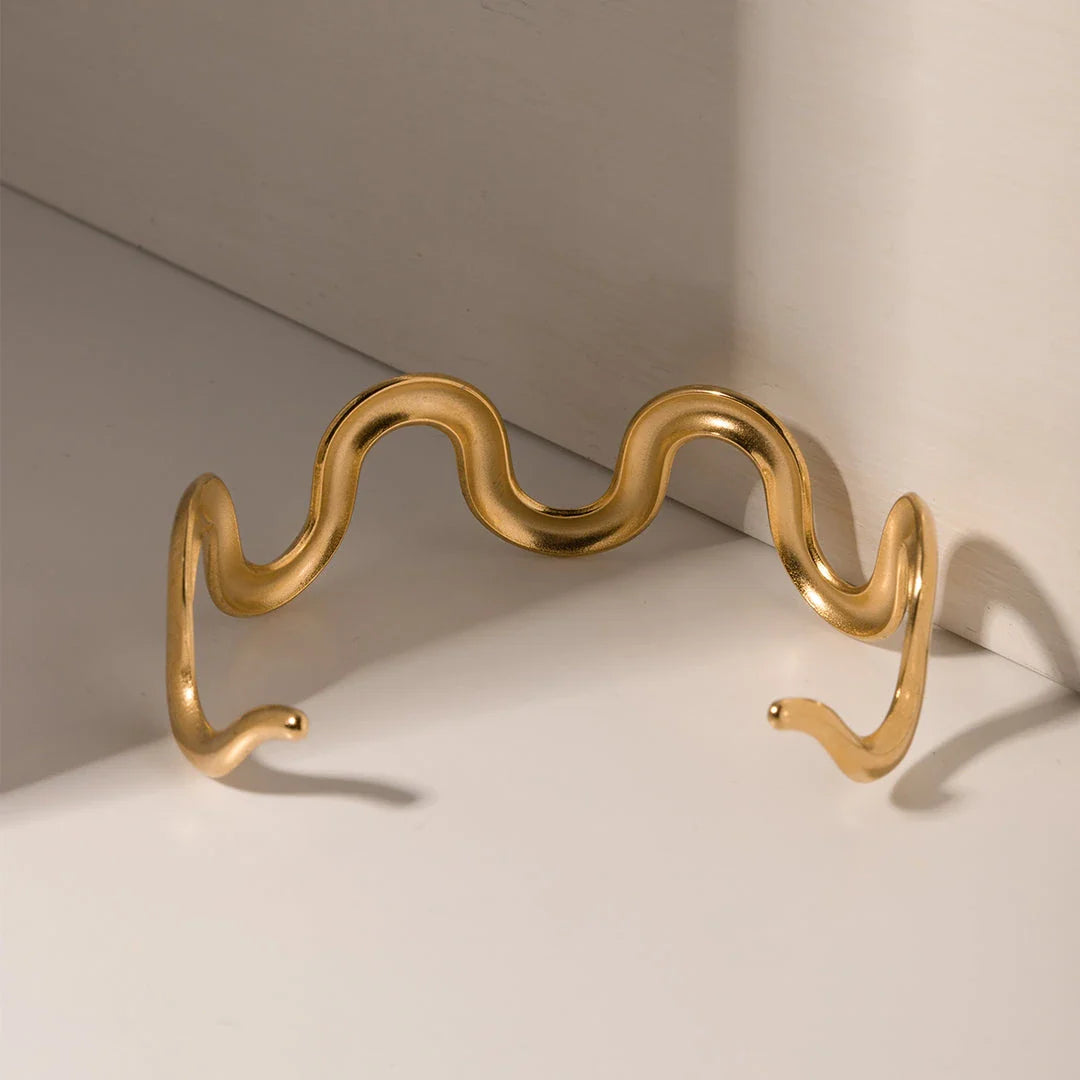 Elegant 18K gold-plated stainless steel wave bracelet and necklace set for women, showcasing a unique contemporary design with adjustable drawstring closure