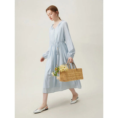 A woman wearing a long-sleeved, midi-length dress in a French pastoral style with an empire waistline and A-line silhouette.