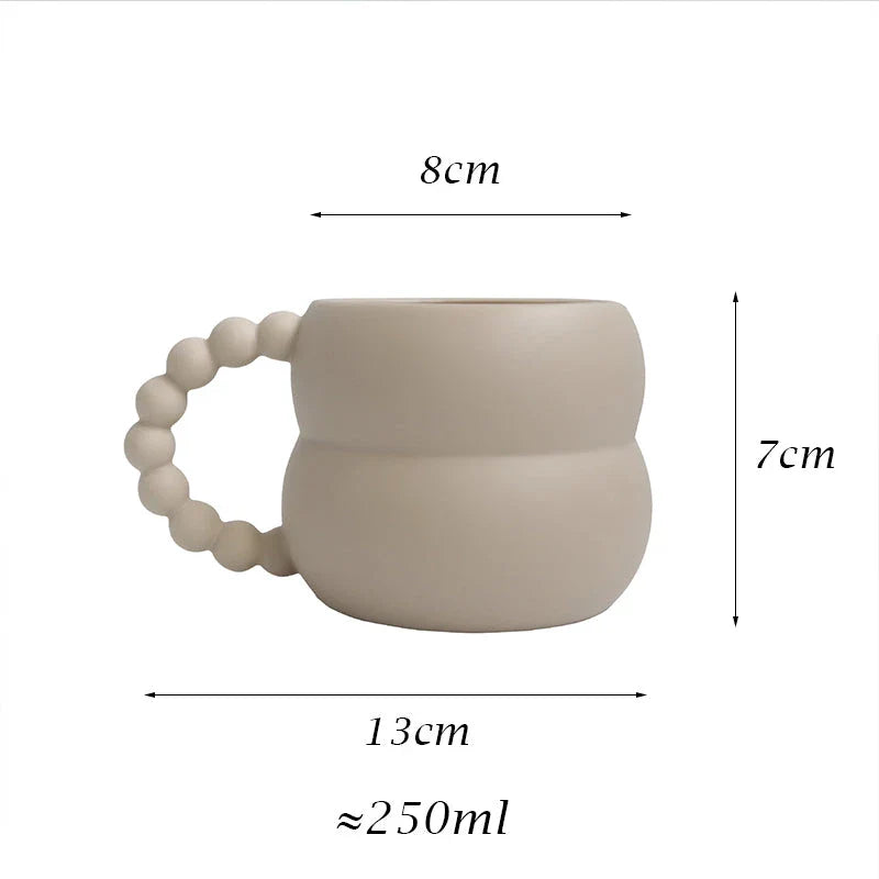 Handmade ceramic mug in beige and blue Nordic-inspired design, with a comfortable handle for enjoying hot or cold beverages.