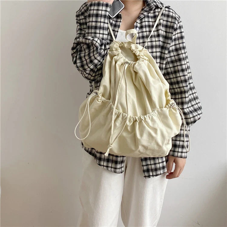 A stylish drawstring bucket bag in white, black, or brown colour options, featuring a spacious interior and adjustable closure for modern British women.