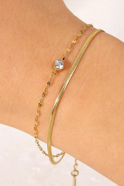 Close-up of a gold-coloured double-layered bracelet with sparkling rhinestones, on a white background.