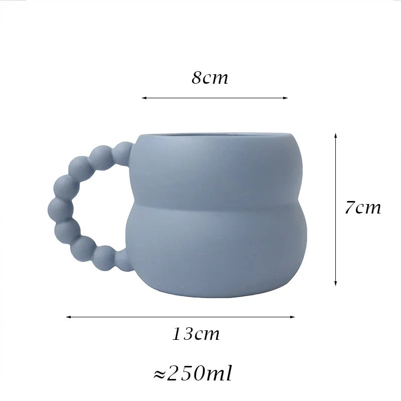 Handmade ceramic mug in beige and blue Nordic-inspired design, with a comfortable handle for enjoying hot or cold beverages.
