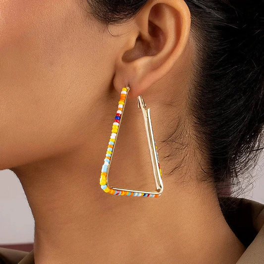 Colourful beaded triangle hoop earrings in gold metal with vibrant beadwork