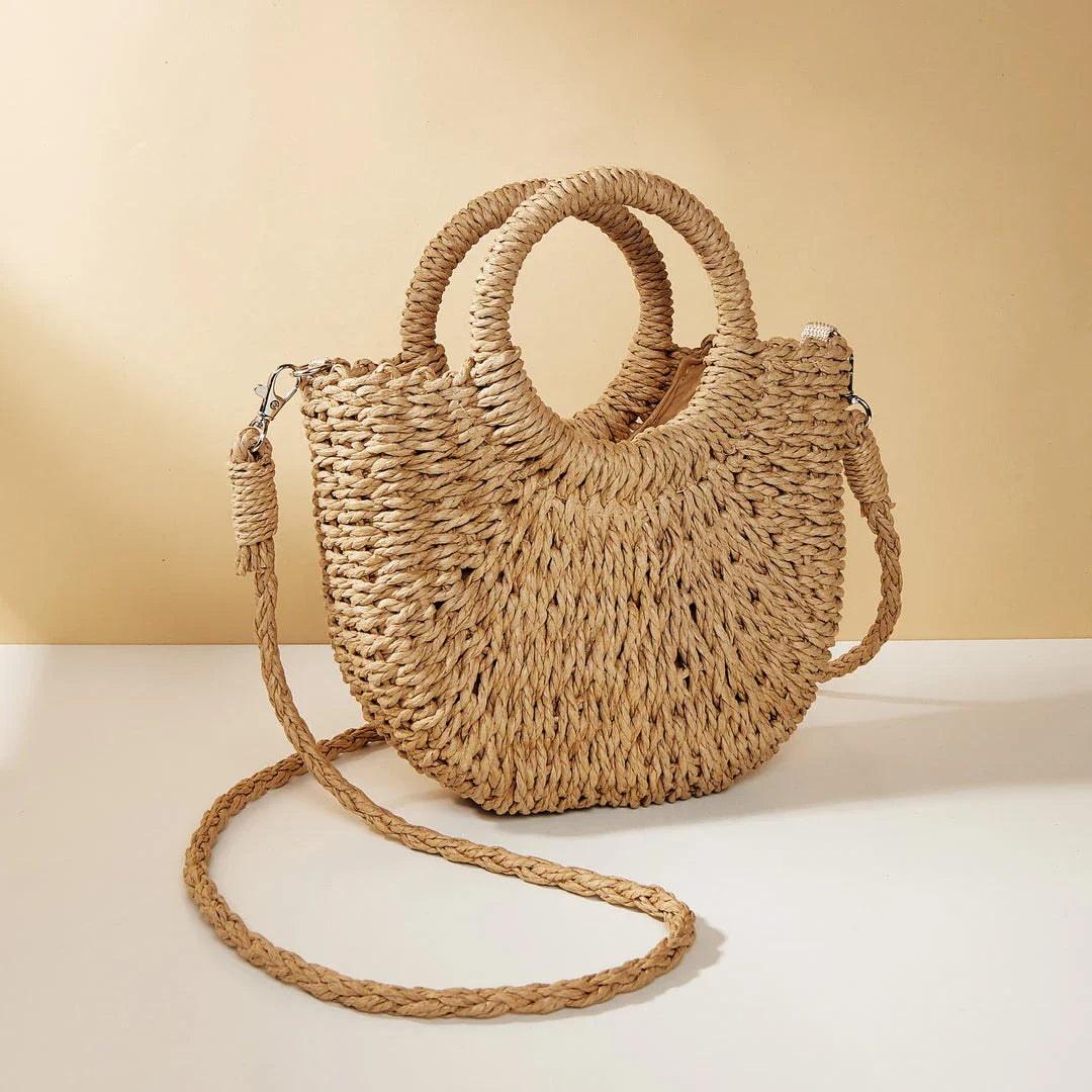 Stylish straw woven women's beach shoulder bag in a half-moon shape, featuring a cotton lining and string closure for a minimalist, bohemian-inspired look.