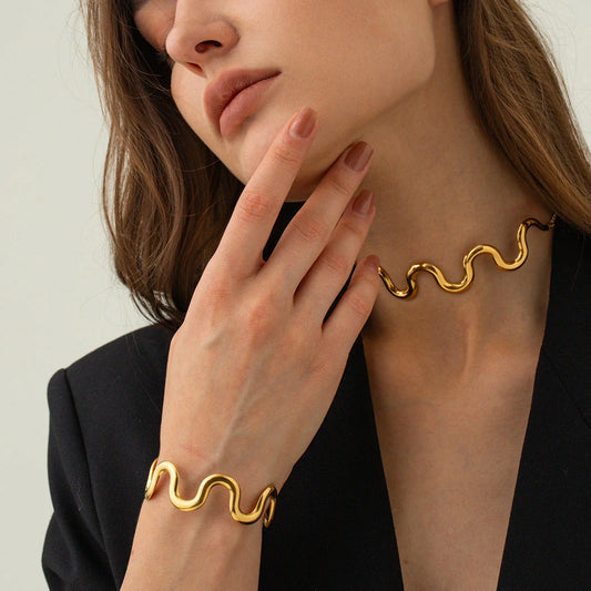 Elegant 18K gold-plated stainless steel wave bracelet and necklace set for women, showcasing a unique contemporary design with adjustable drawstring closure