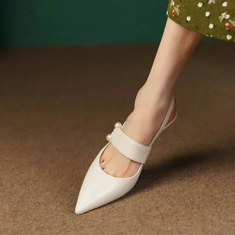 Pair of white high heel sandals with pearl embellishments, showcasing a unique and fashionable design