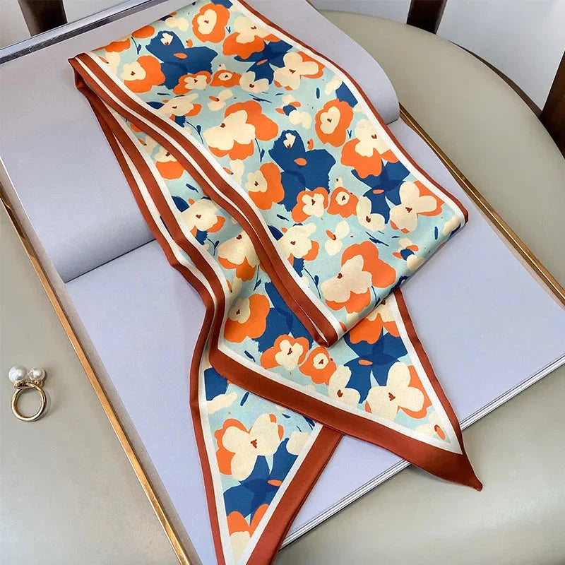 A vibrant floral-patterned silk-feel long scarf that can be worn as a neck accessory, hair tie, or wrist adornment for all occasions.