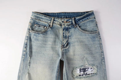 Stylish ripped denim jeans with a unique black and white patch design, perfect for British gentlemen