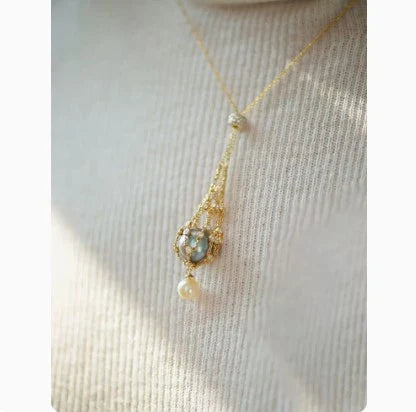 Exquisite 18K gold necklace with a delicate net pocket, inlaid gem, and iridescent shell beads