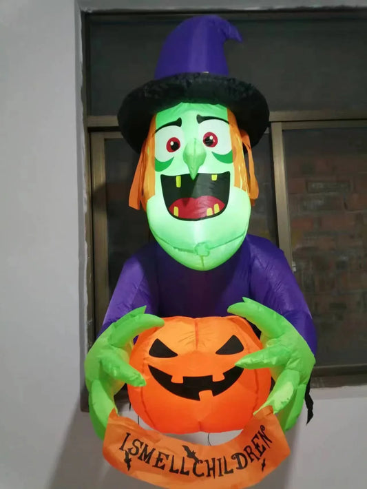 Inflatable Halloween witch decoration holding a spooky pumpkin, set up in a garden or outdoor space