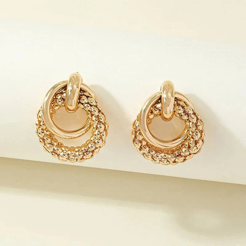 Exquisite gold twist dangle earrings with an intricate geometric design, a bold statement of modern elegance for fashion-forward women.