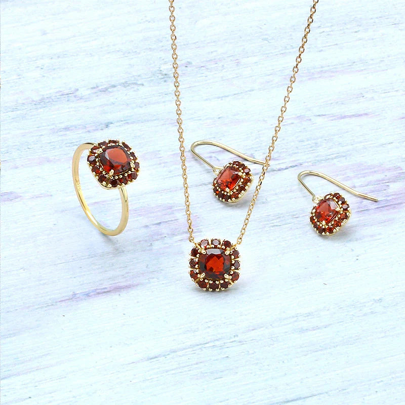 A pair of elegant red pomegranate-inspired earrings with a silver finish and geometric design, showcasing British style and sophistication.