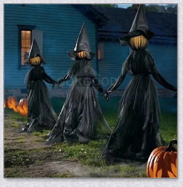 Three tall, black-robed witch figures with faceless glowing heads, standing together and holding hands, creating a spooky outdoor Halloween display