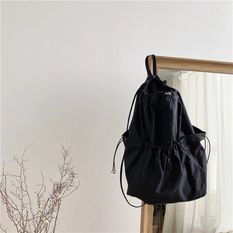 A stylish drawstring bucket bag in white, black, or brown colour options, featuring a spacious interior and adjustable closure for modern British women.