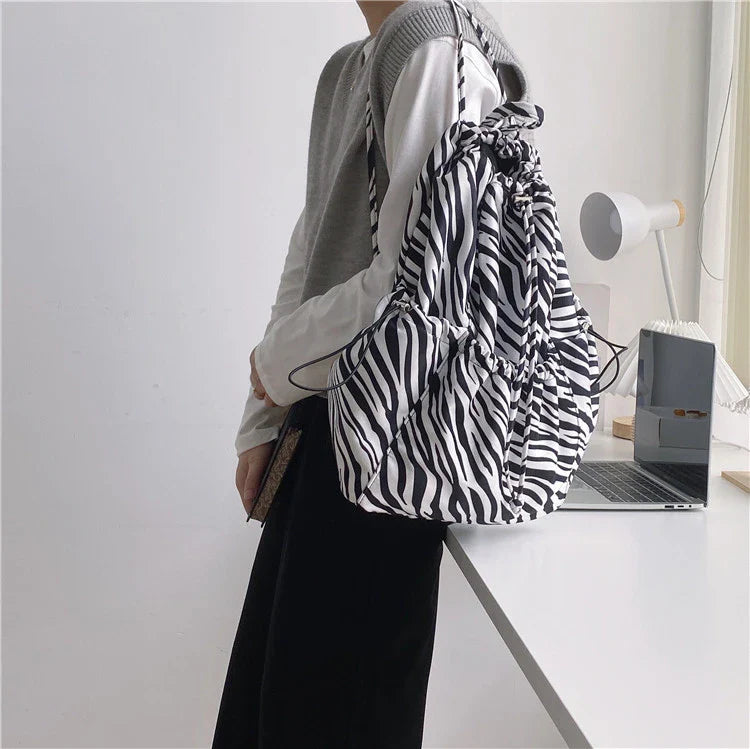 A stylish drawstring bucket bag in white, black, or brown colour options, featuring a spacious interior and adjustable closure for modern British women.