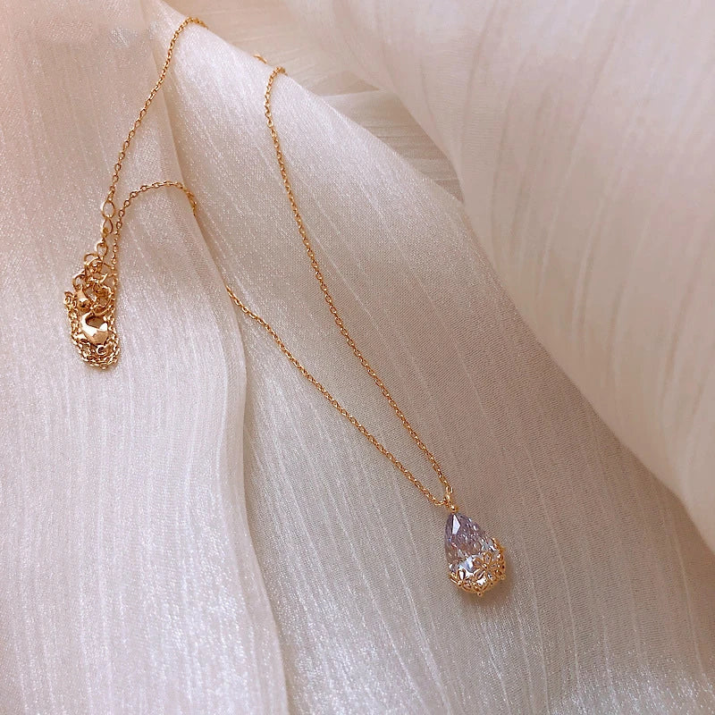 Close-up shot of a silver-plated crystal water drop pendant necklace on a plain background