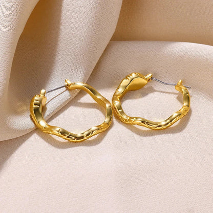 A pair of gold-toned stainless steel hoop earrings, showcasing a classic and sophisticated design