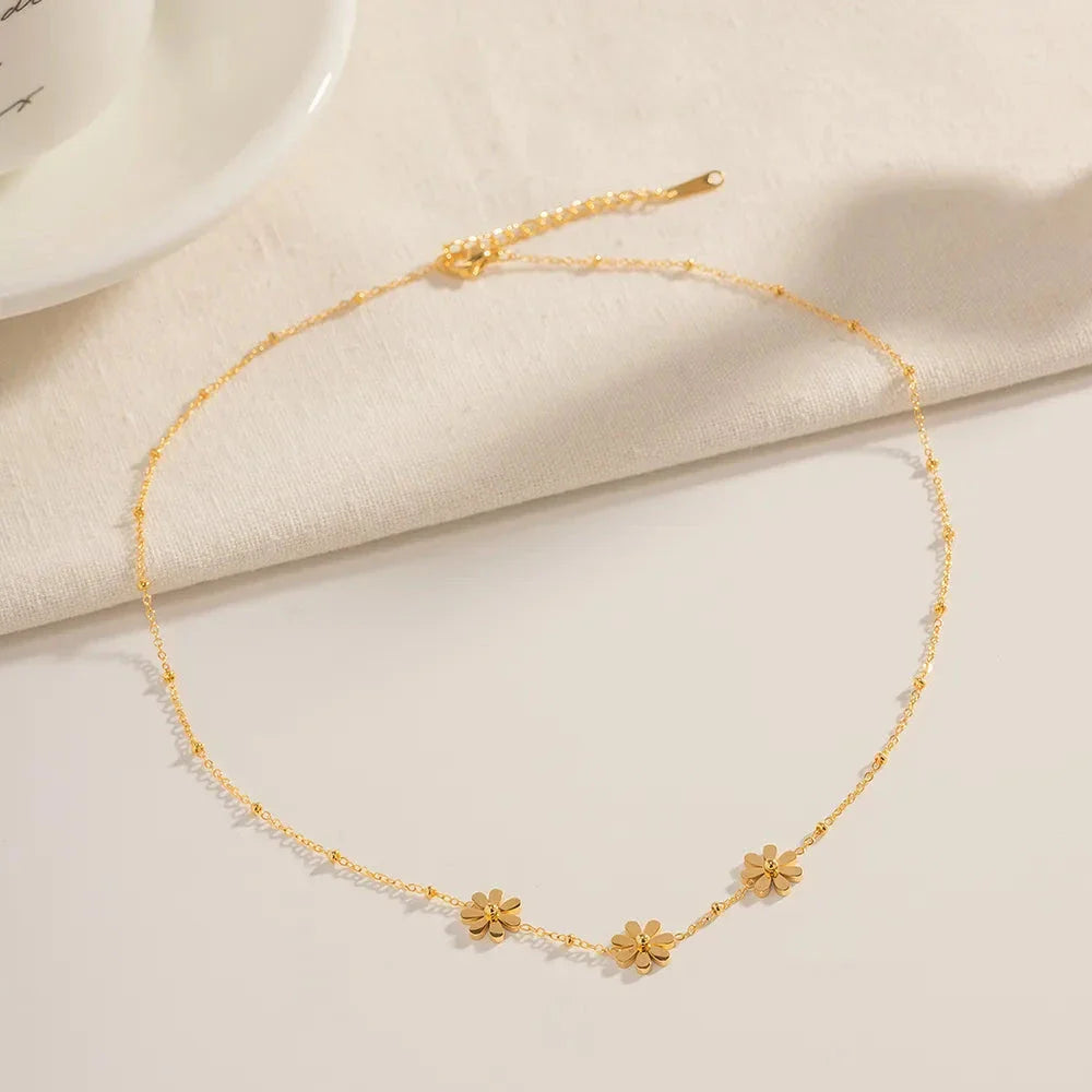 Exquisite 18-carat gold-plated necklace featuring three delicate daisy pendants on a stainless steel chain, embodying timeless British elegance and sophistication.