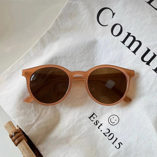 A pair of stylish, retro-inspired round sunglasses with a white frame, providing UV protection and a chic, contemporary look.