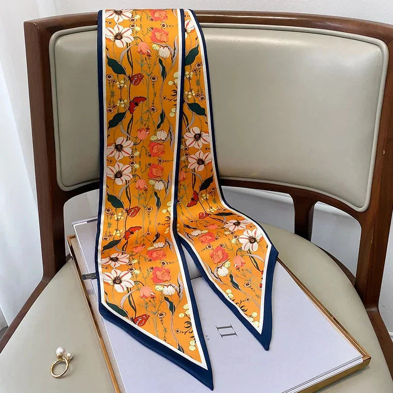 A vibrant floral-patterned silk-feel long scarf that can be worn as a neck accessory, hair tie, or wrist adornment for all occasions.