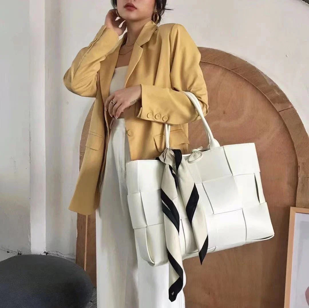 Exquisitely crafted leather tote bag with a timeless woven design, embodying British elegance and quality.