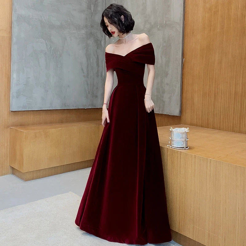 Off-shoulder wine red bridal dress with long, flowing skirt and tight waist for a sophisticated, elegant look