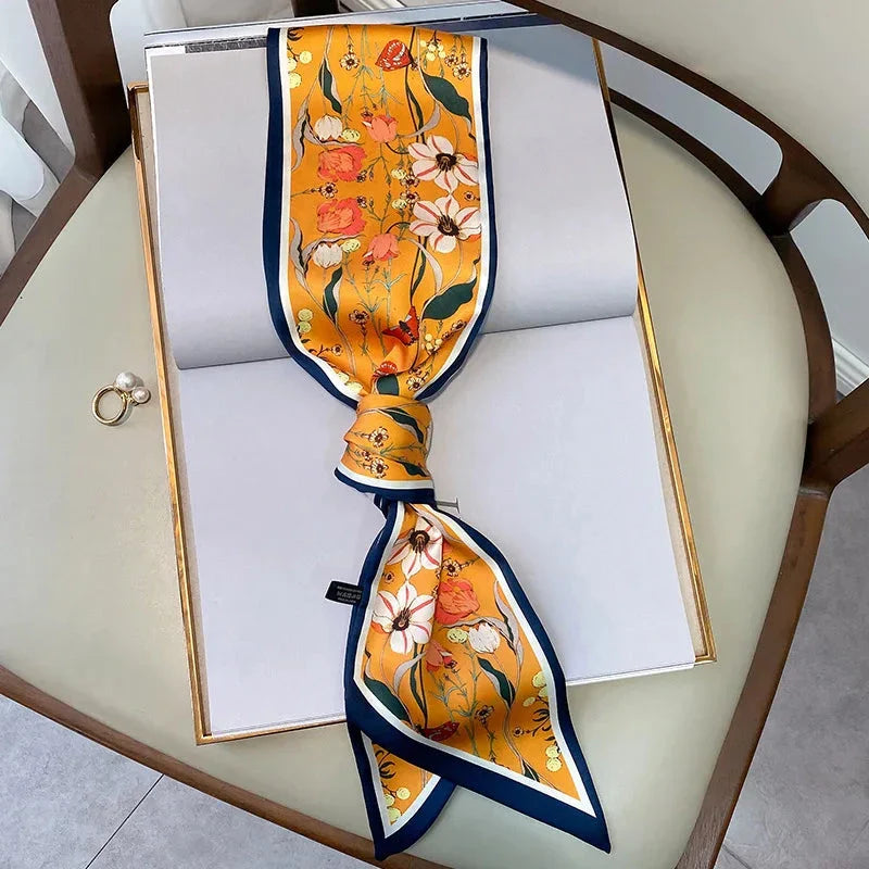 A vibrant floral-patterned silk-feel long scarf that can be worn as a neck accessory, hair tie, or wrist adornment for all occasions.