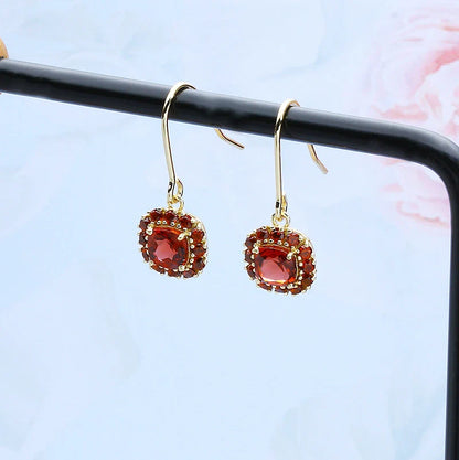 A pair of elegant red pomegranate-inspired earrings with a silver finish and geometric design, showcasing British style and sophistication.
