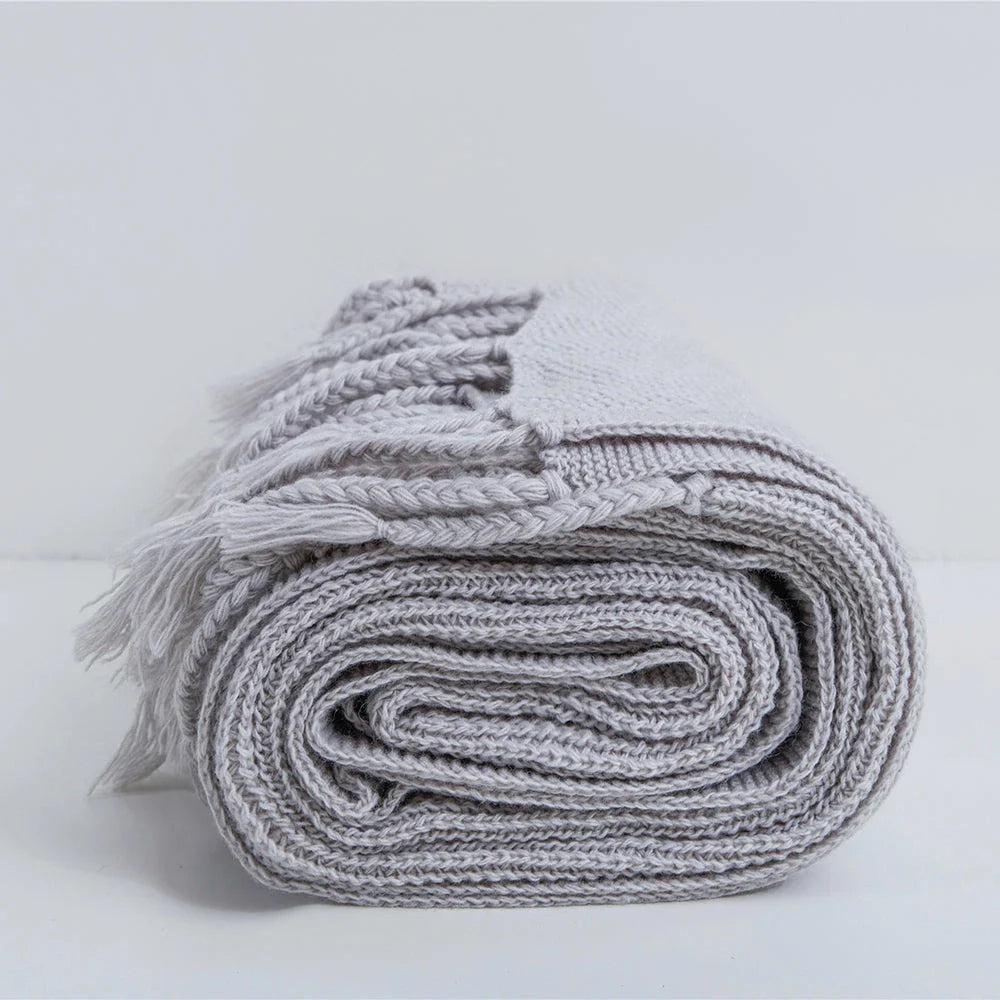 Luxurious Nordic-style wool knitted throw blanket in grey colour, featuring a solid pattern and elegant tassel design