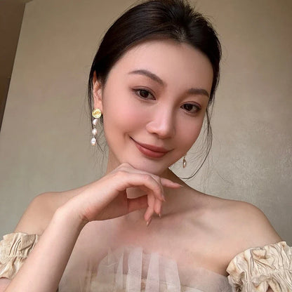 Elegant pearl and gold plated earrings with a long, eye-catching design