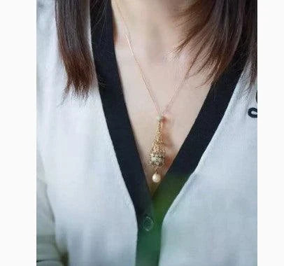 Exquisite 18K gold necklace with a delicate net pocket, inlaid gem, and iridescent shell beads