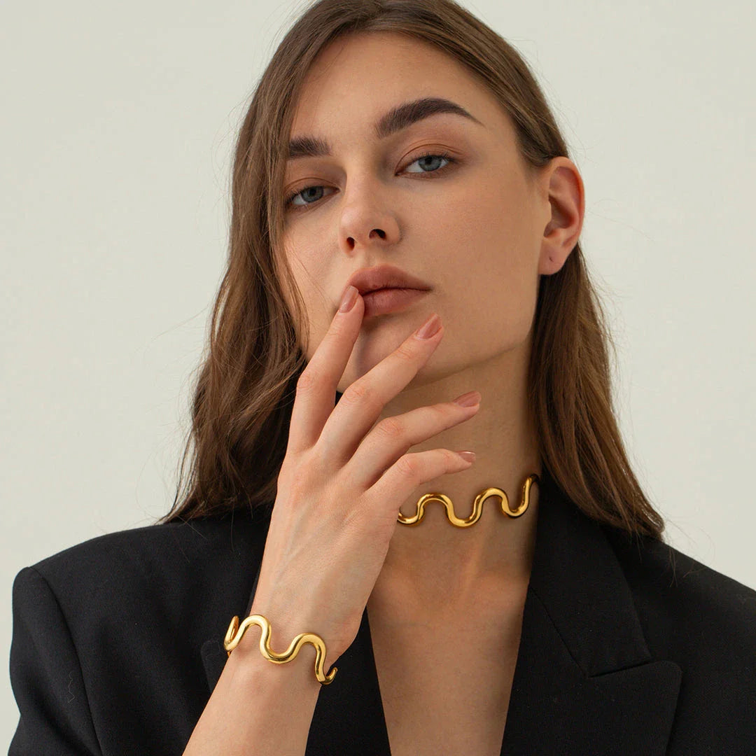 Elegant 18K gold-plated stainless steel wave bracelet and necklace set for women, showcasing a unique contemporary design with adjustable drawstring closure