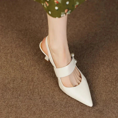 Pair of white high heel sandals with pearl embellishments, showcasing a unique and fashionable design