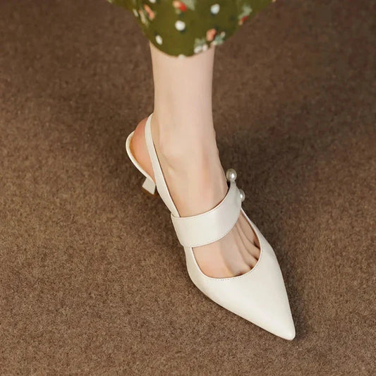 Pair of white high heel sandals with pearl embellishments, showcasing a unique and fashionable design