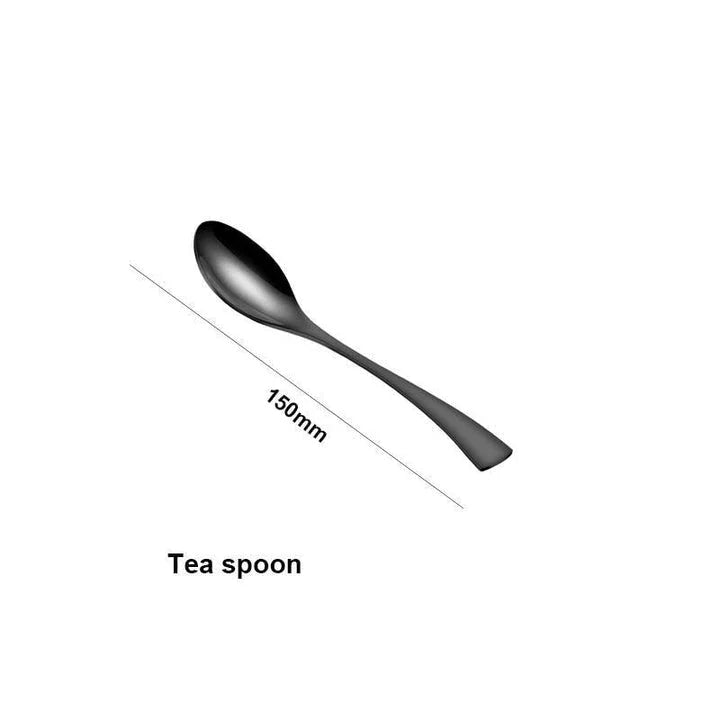 A stylish set of black stainless steel flatware, including a teaspoon, knife, and fork, on a white background.