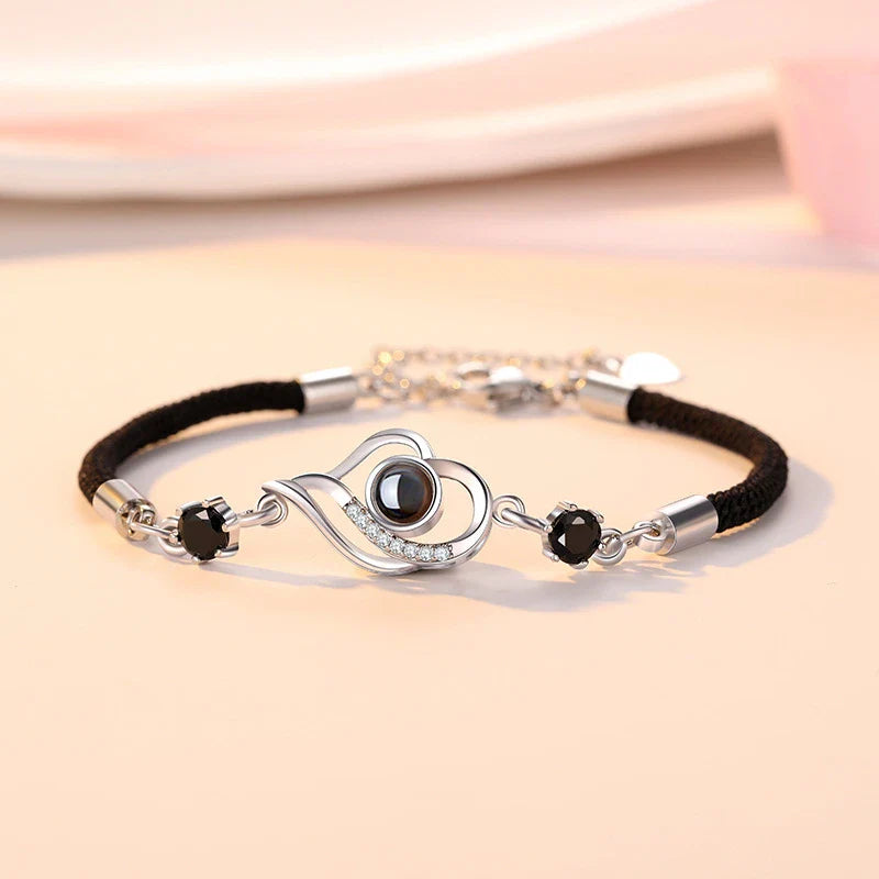 A rose gold or platinum plated copper charm bracelet featuring the phrase 'I Love You' inscribed in 100 languages.