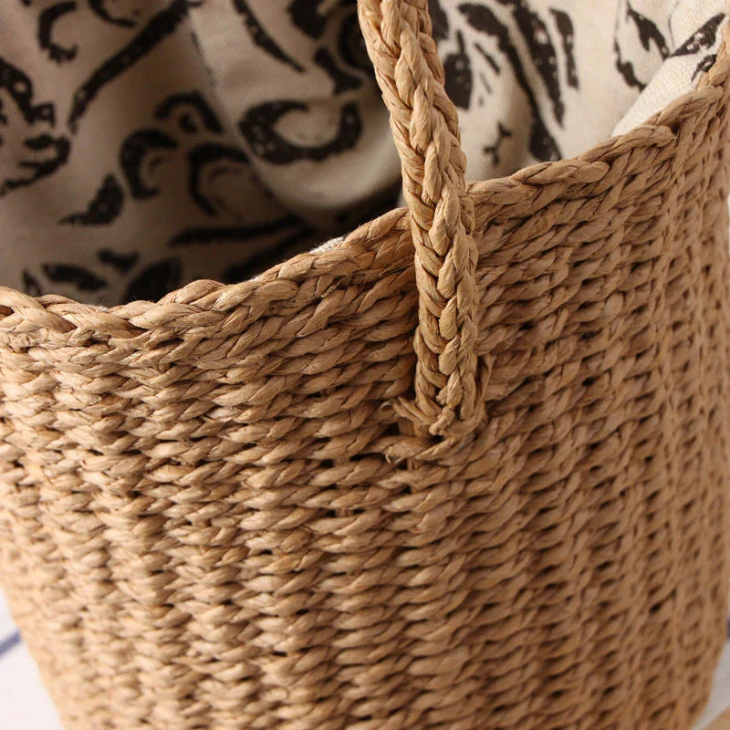 Elegant hand-crafted straw bucket bag in camel or beige, featuring a compact and lightweight design for versatile British summer style